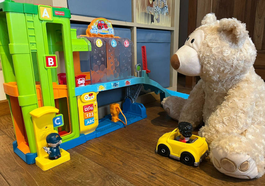 Een knuffelbeer speelt met een speelgarage